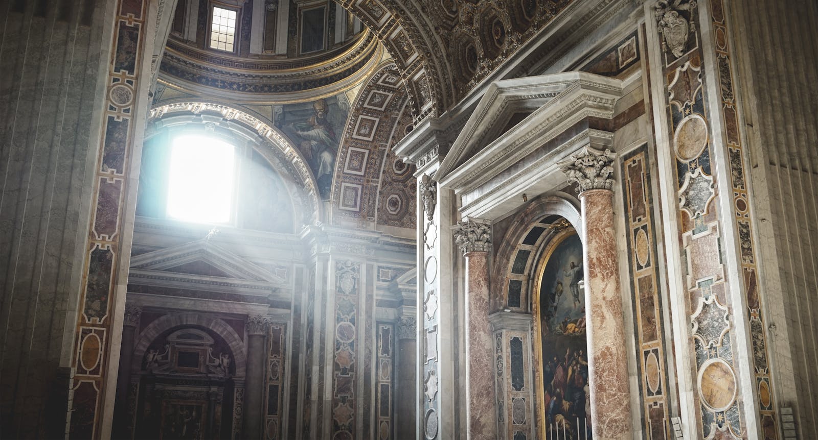 A photo of the inside of a cathedral. A majestic view of a cathedral's ornate interior with sunrays illuminating the columns.