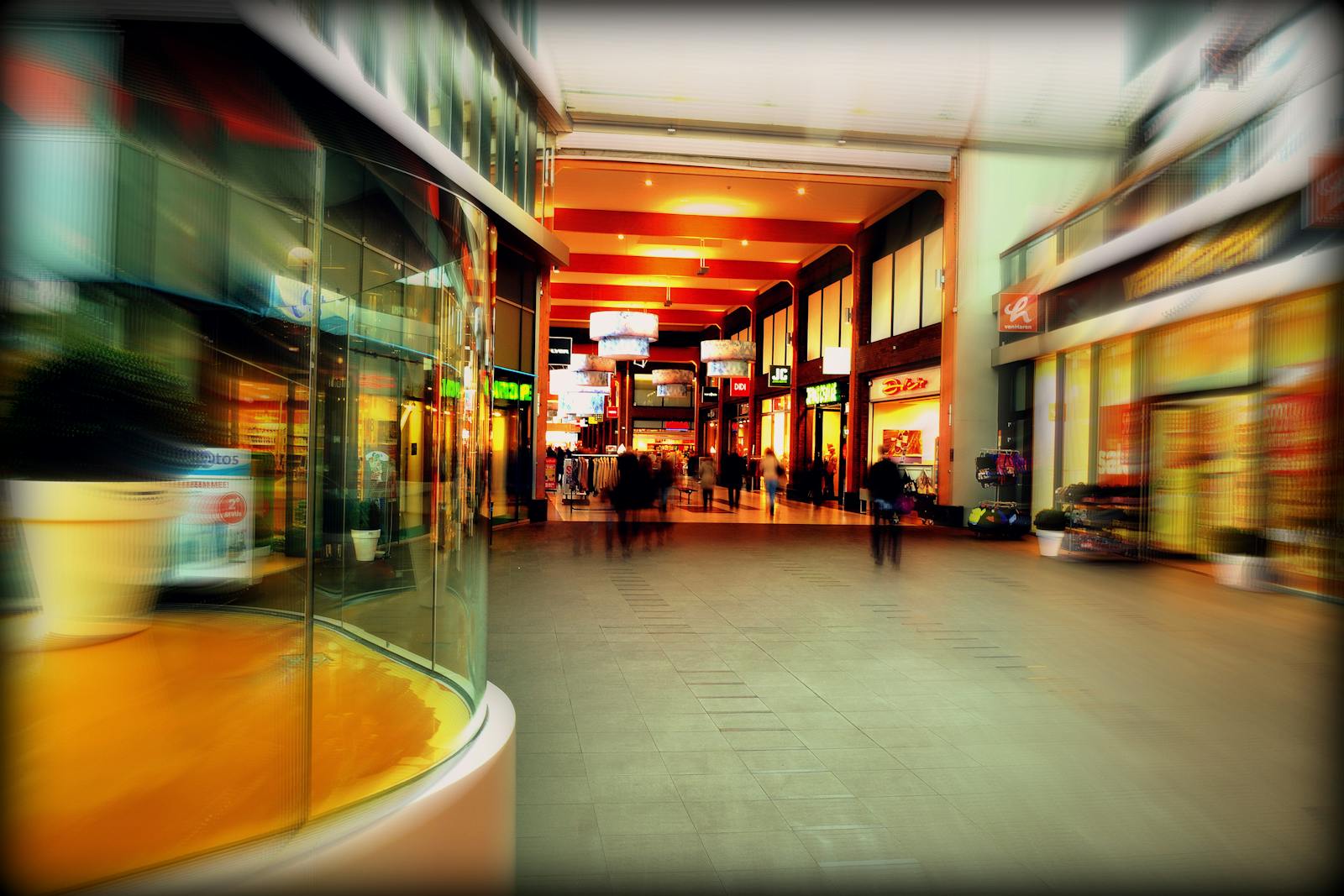 A photo of a shopping mall. Explore the lively atmosphere of a modern shopping mall in Hoofddorp, Netherlands, captured with vibrant colors and motion blur.