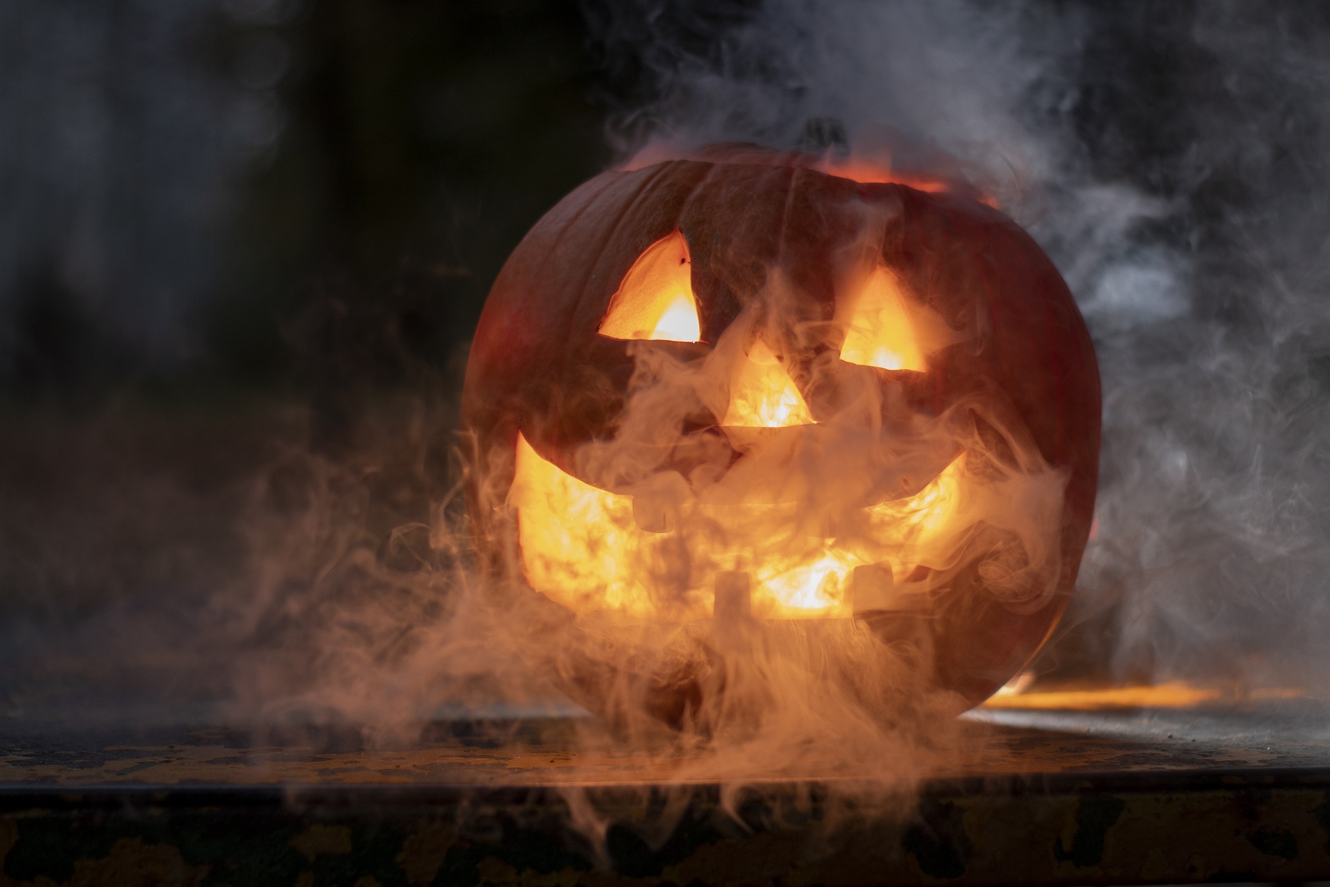 A carved pumpkin surrounded by smoke. A carved pumpkin, warmly lit from inside, surrounded by smoke.