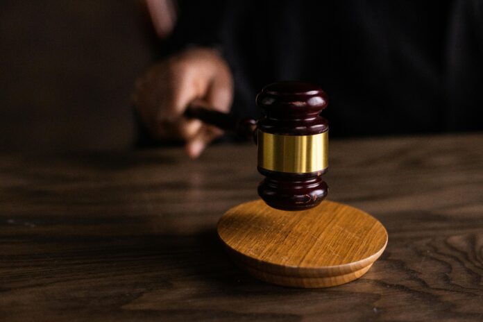 A judge holding a hammer and hitting a gavel.