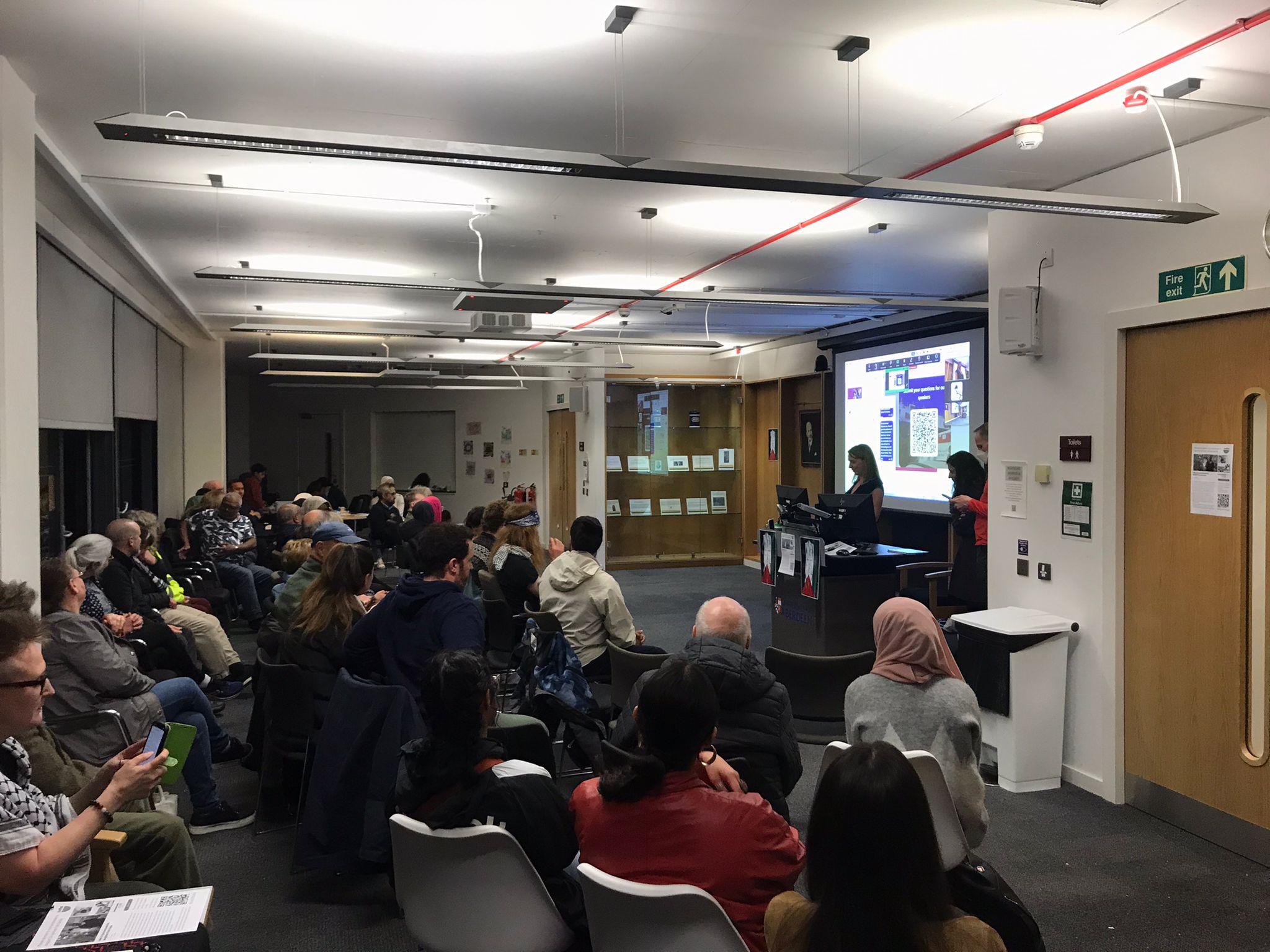 SuttieCentreConferenceRoom Suttie Centre Conference Room filled with people holding a vigil.