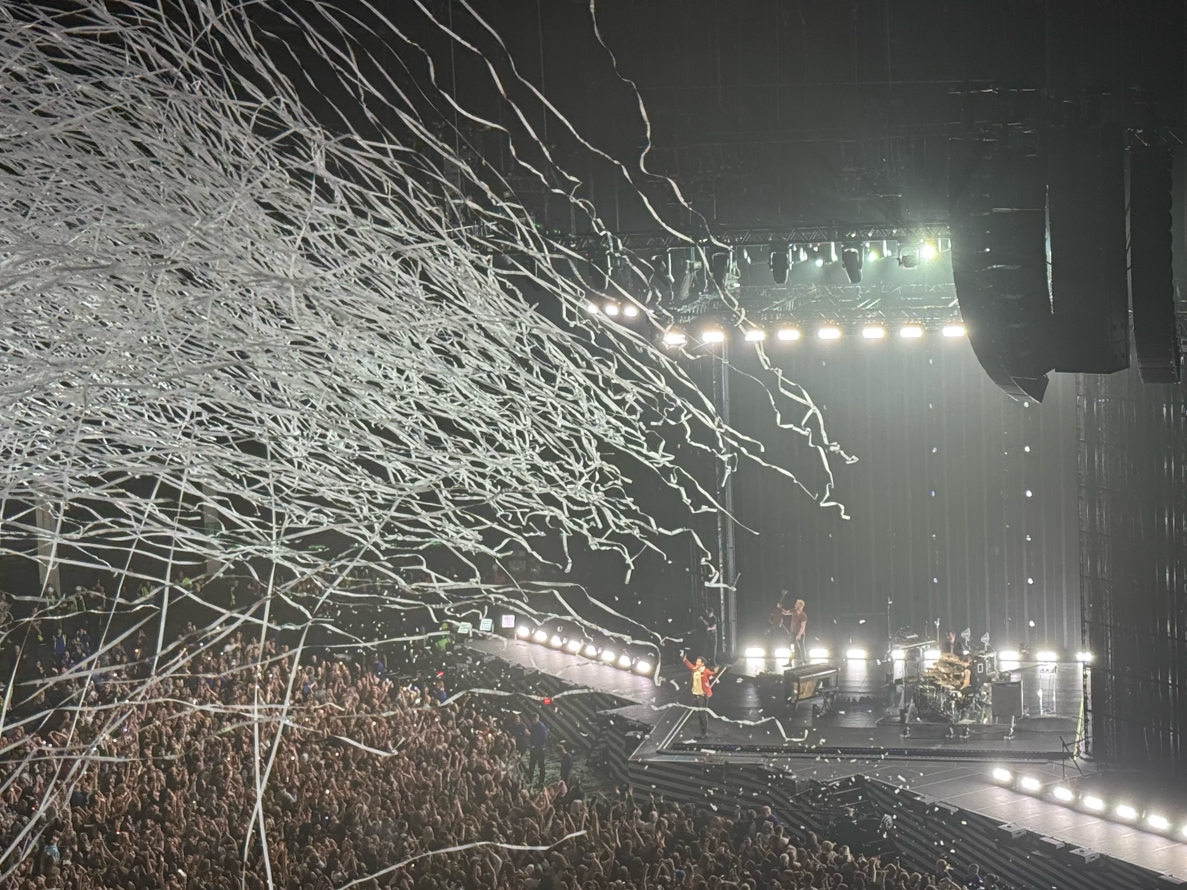 The Script performing in Glasgow, 2024. A wide shot of the crowd and a stage. The Script band are on stage as white streamers fly over the crowd.