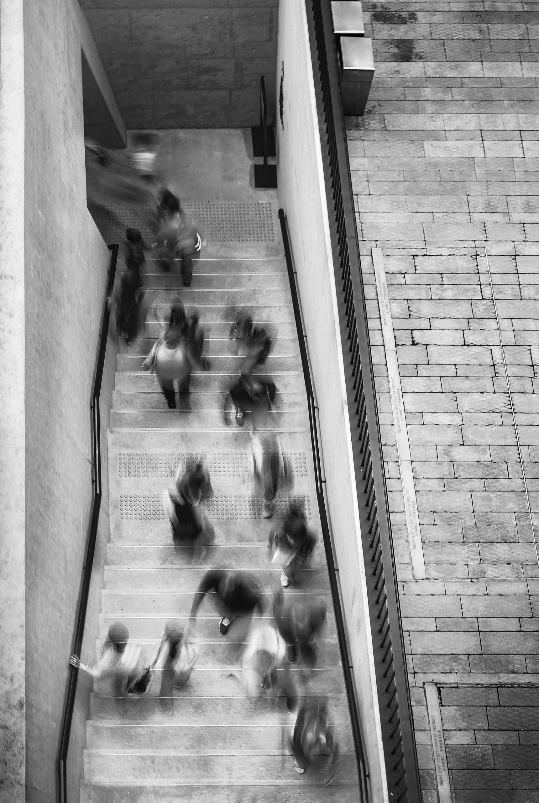 Freshers Fayre Opine Black and white blurry shot of students in stairwell.