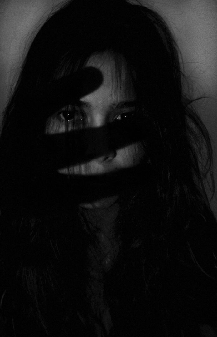 Black and white image of woman, face partially obscured by black pen.
