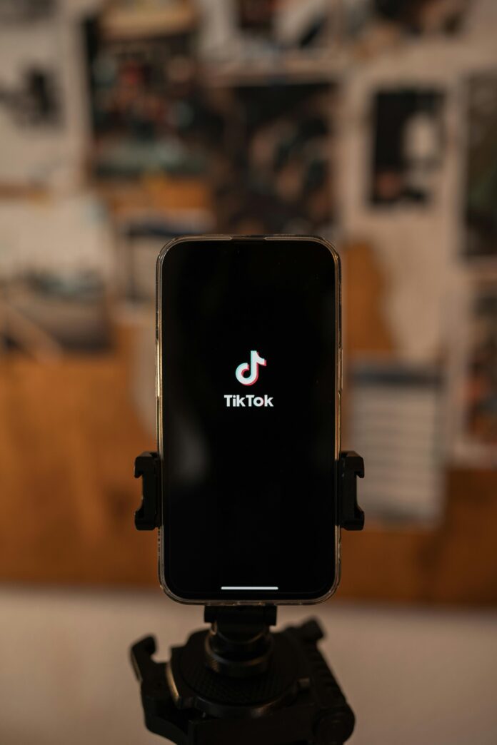 Mobile phone on a tripod with TikTok logo on screen.