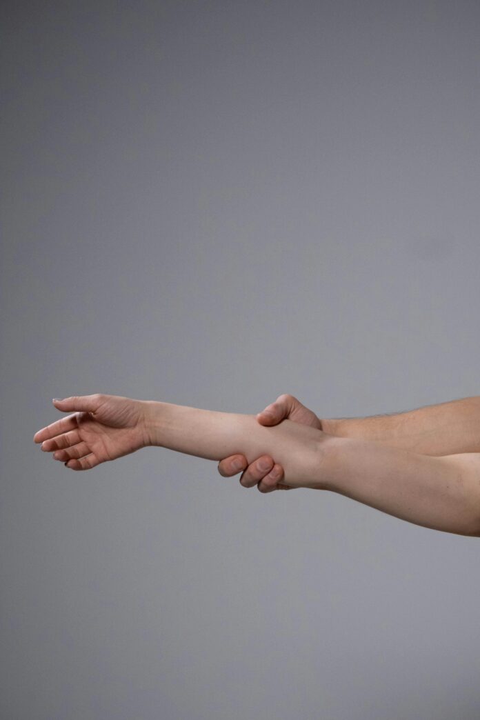 One hand holding another person's forearm.