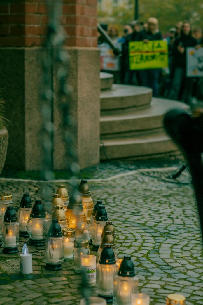 Lit candles on the ground with protesting crowd in the background.